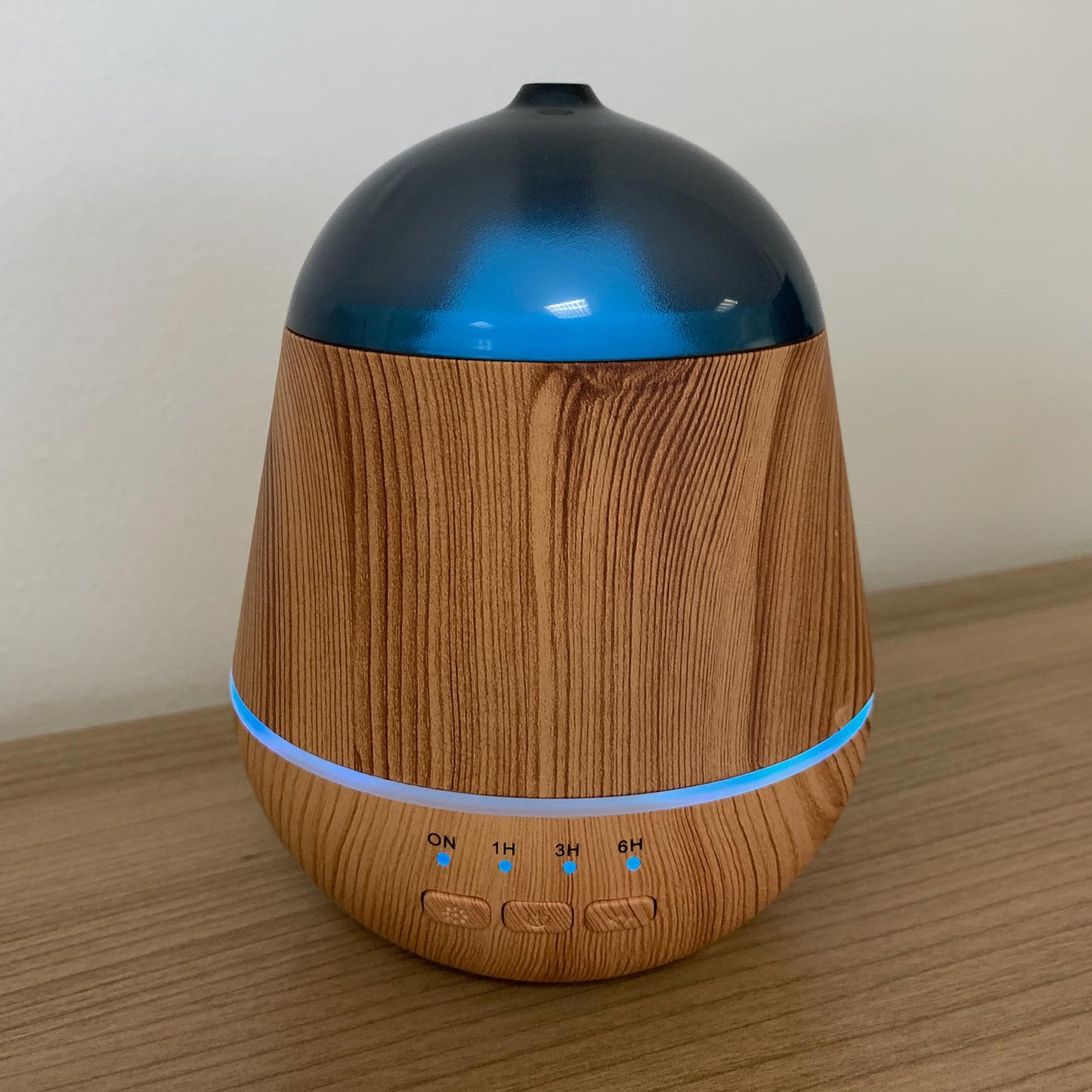 Wooden-textured diffuser with blue top on a wooden surface
